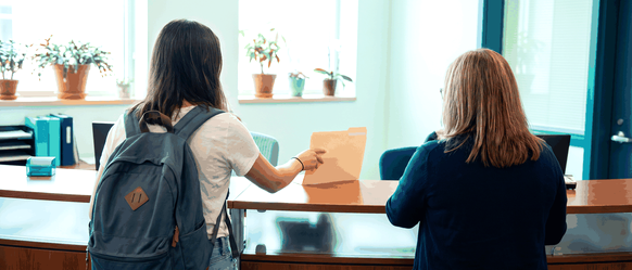 A student handing papers to a college admissions office to get a provincial attestation letter