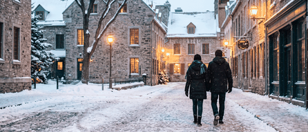 A couple walking on a snowy Quebec City street, one on a spouse open work permit